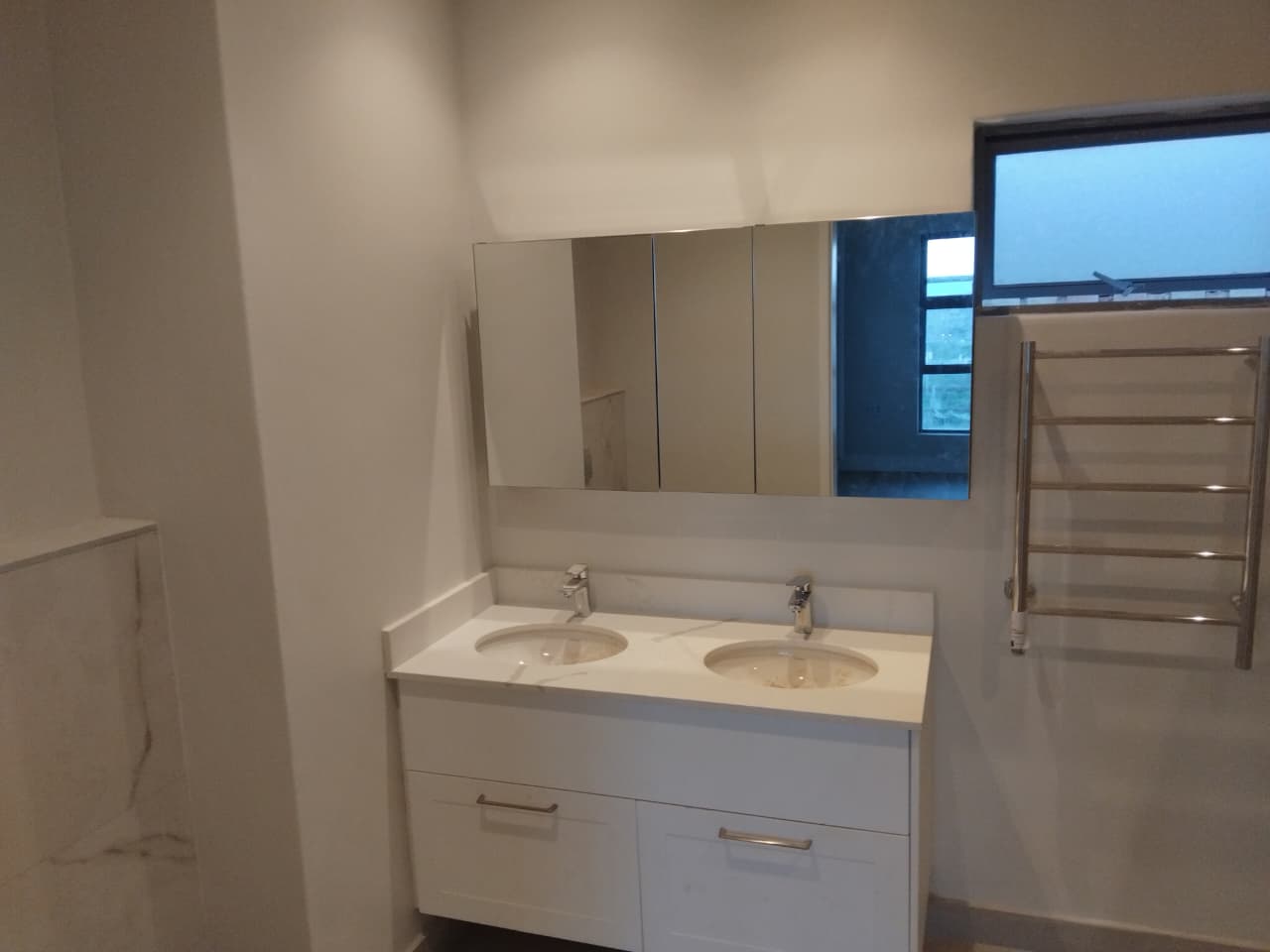 Double basin vanity with mixer taps and a wall-mounted mirror cabinet in a bathroom