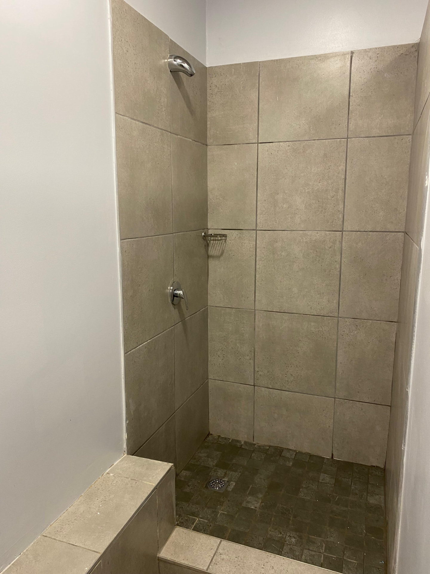 Fully tiled walk-in shower with a wall shower head, mixer and floor drain outlet